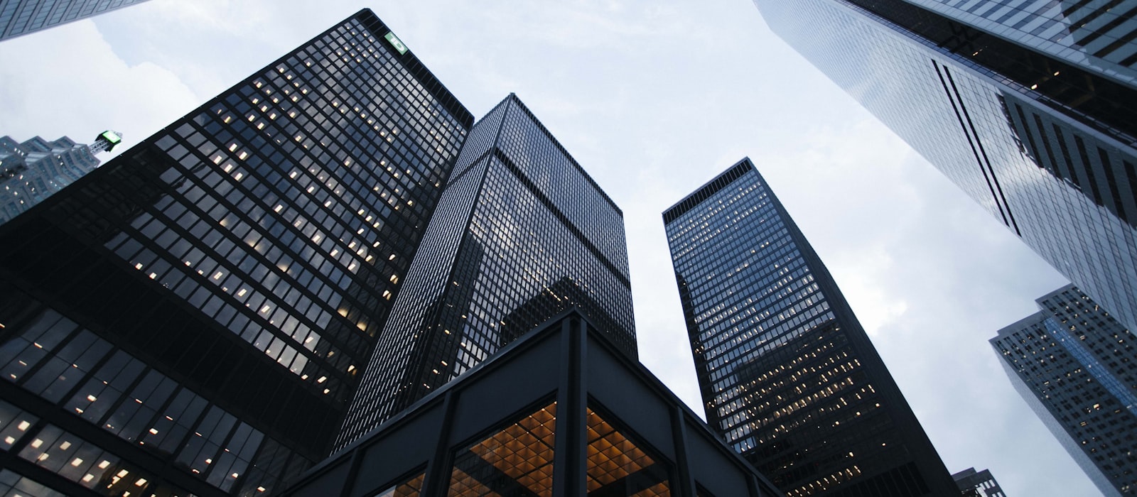 Looking up between dark glass towers in a financial district at dusk